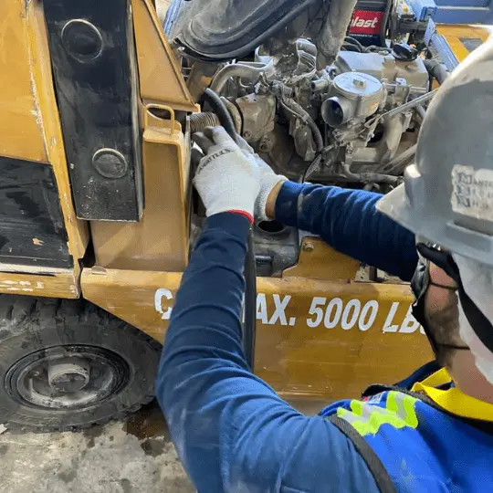 operador realizando mantenimiento a un montacargas